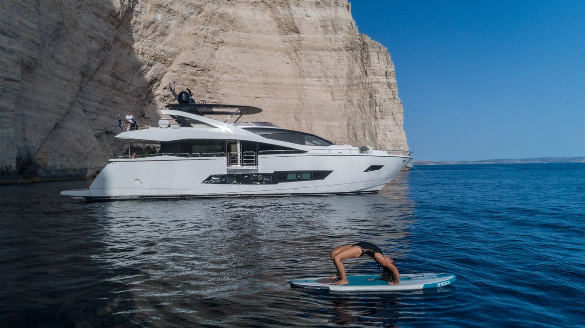 Sunseeker 86 JUPJU at anchor with a paddleboard in the clear water off Malta